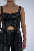 Person wearing a black outfit with suspenders on a white background