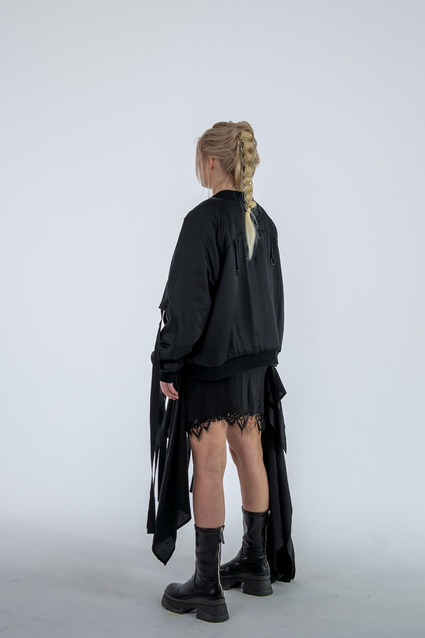 Person wearing a black outfit with a long skirt and boots on a white background