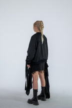 Person wearing a black outfit with a long skirt and boots on a white background