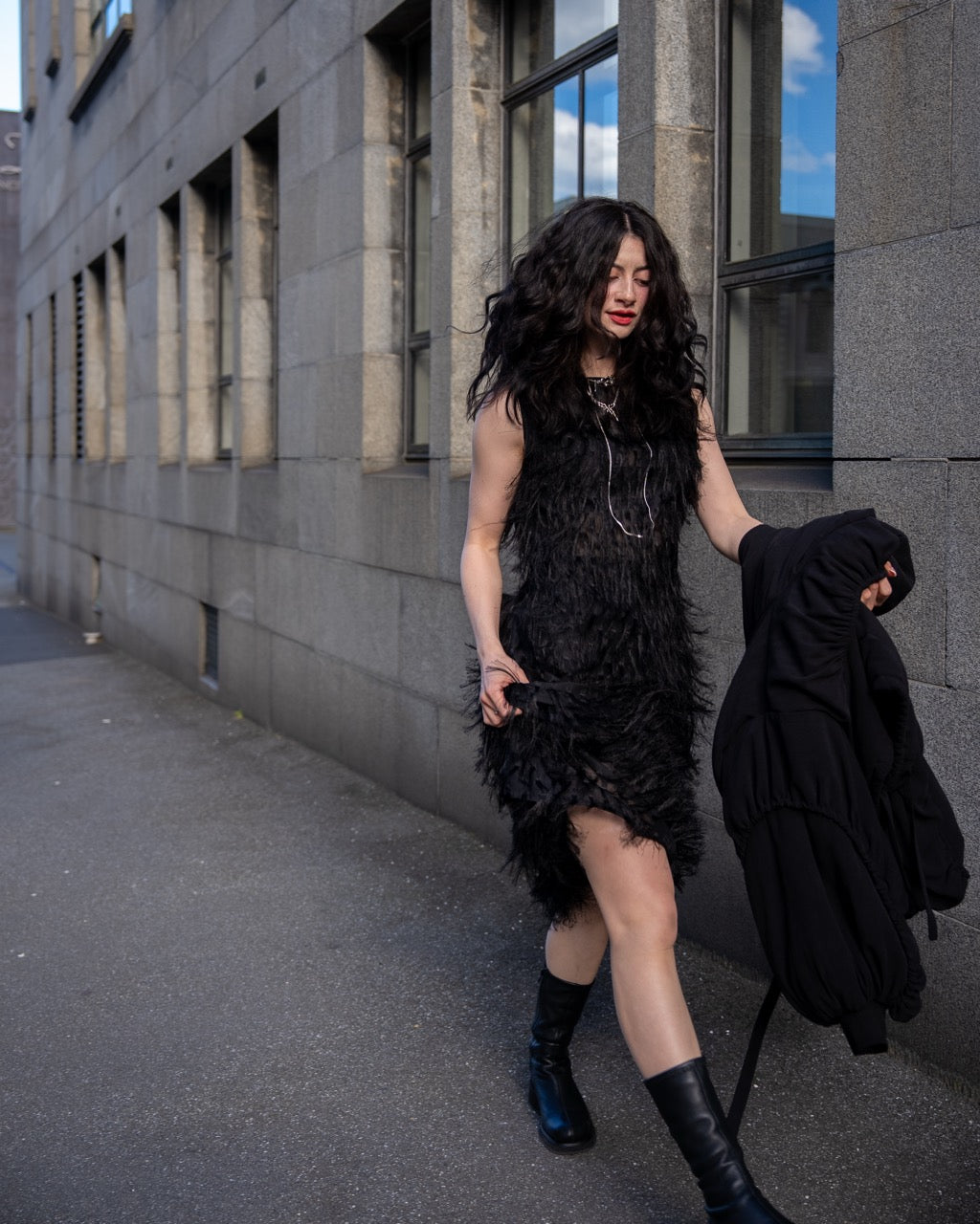 Person wearing a black sleeveless dress with fray details handmade by Rhian walking on a Dunedin street