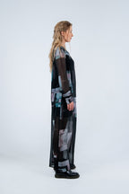 Woman wearing a long, dark-colored dress with abstract patterns on a white background