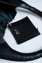 Black leather wallet with chrome Rhian emblem on a white surface