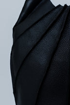 Close-up of black textured leather handbag on a light gray background