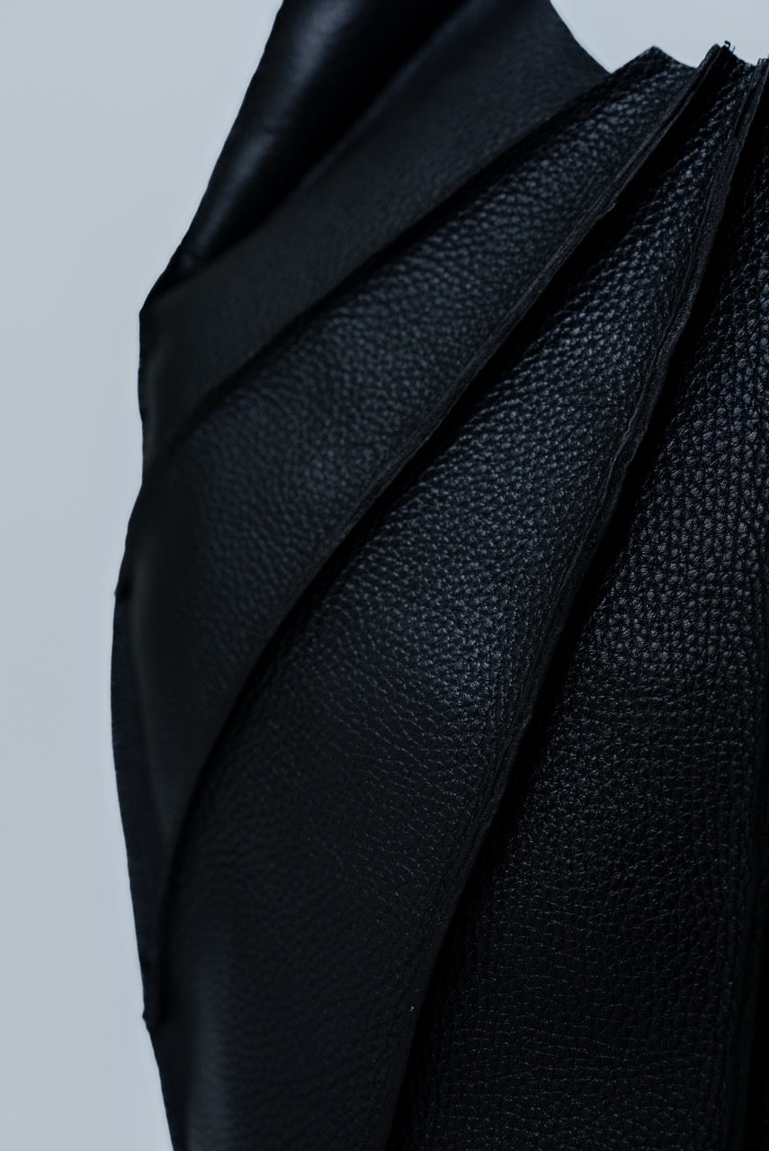 Close-up of black textured leather handbag on a light gray background