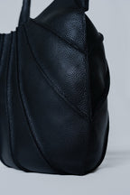 Black leather handbag on a light gray background