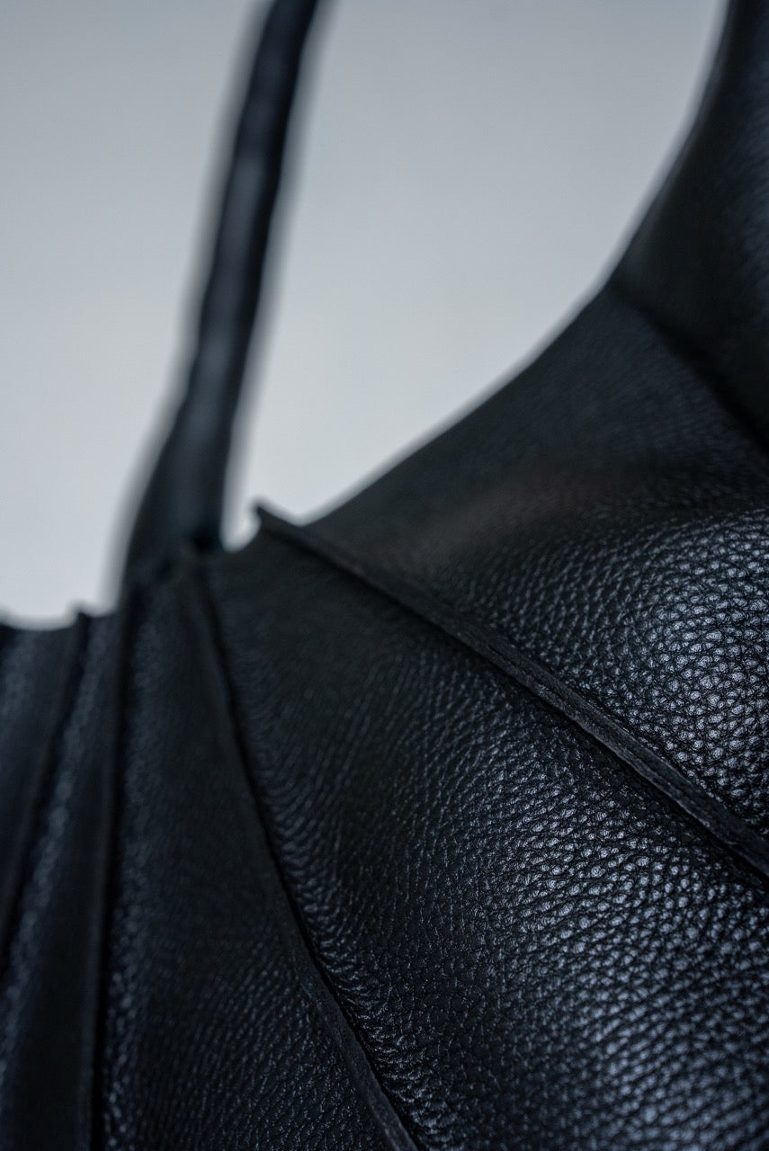 Close-up of black textured leather handbag on a light gray background