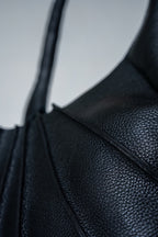 Close-up of black textured leather handbag on a light gray background