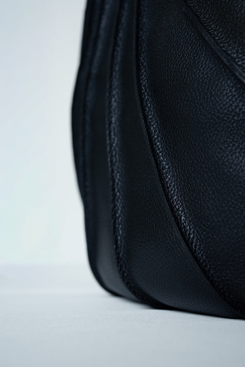 Close-up of black textured leather handbag on a light gray background