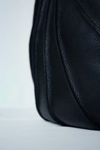 Close-up of black textured leather handbag on a light gray background