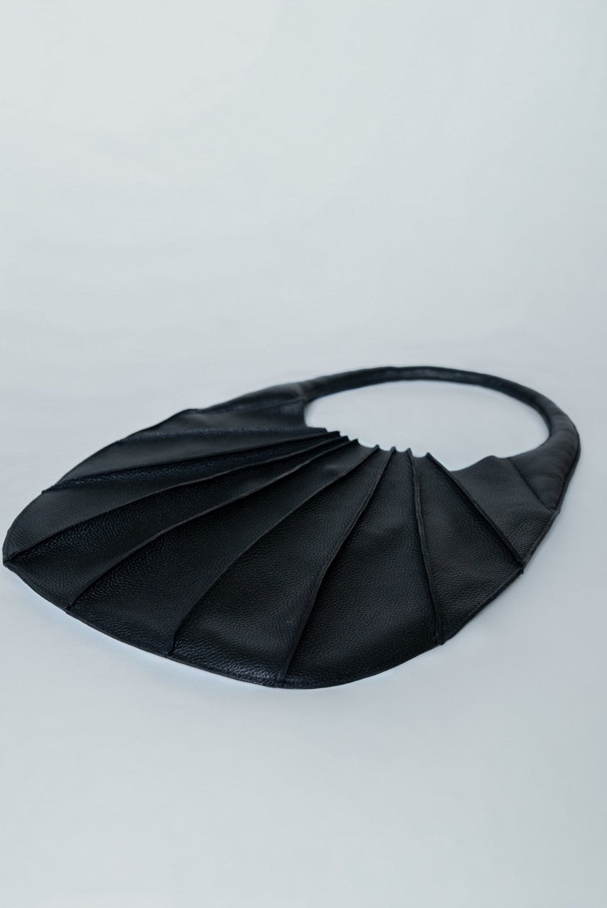 Black pleated handbag on a light gray background