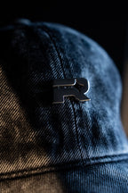 Close-up of a blue denim cap with a black logo on a dark background