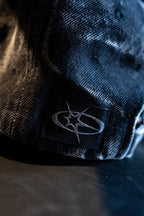 Close-up of a dark blue cap with a logo on a dark surface