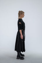 Person wearing a black dress with cut-out shoulders on a white background