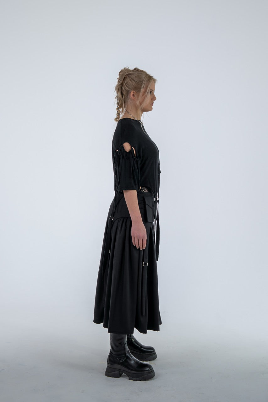 Person wearing a black dress with cut-out shoulders on a white background
