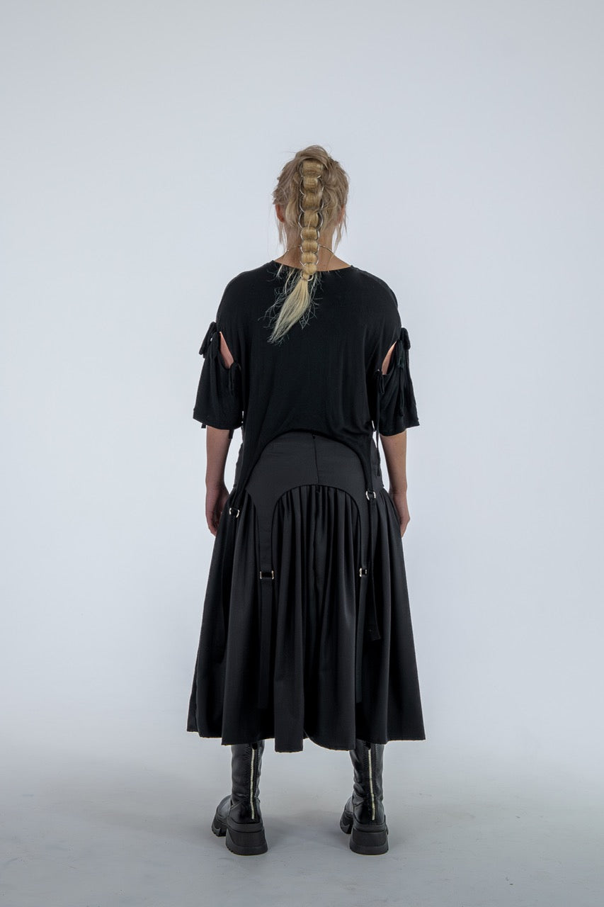 Person wearing a black dress with cut-out sleeves on a white background