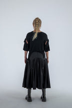Person wearing a black dress with cut-out sleeves on a white background