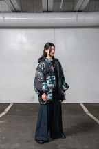 Person wearing a patterned jacket and dark pants in an industrial setting