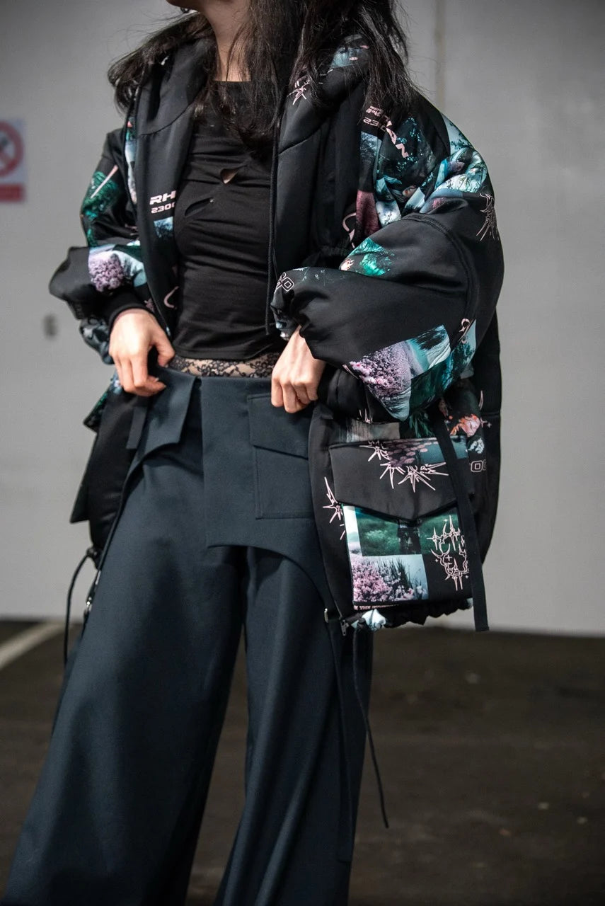 Person wearing a black and green patterned jacket with a plain background