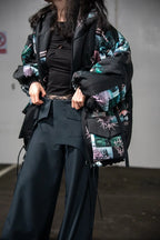 Person wearing a black and green patterned jacket with a plain background