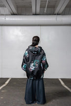 Person wearing a black jacket with colorful floral patterns in an indoor setting.
