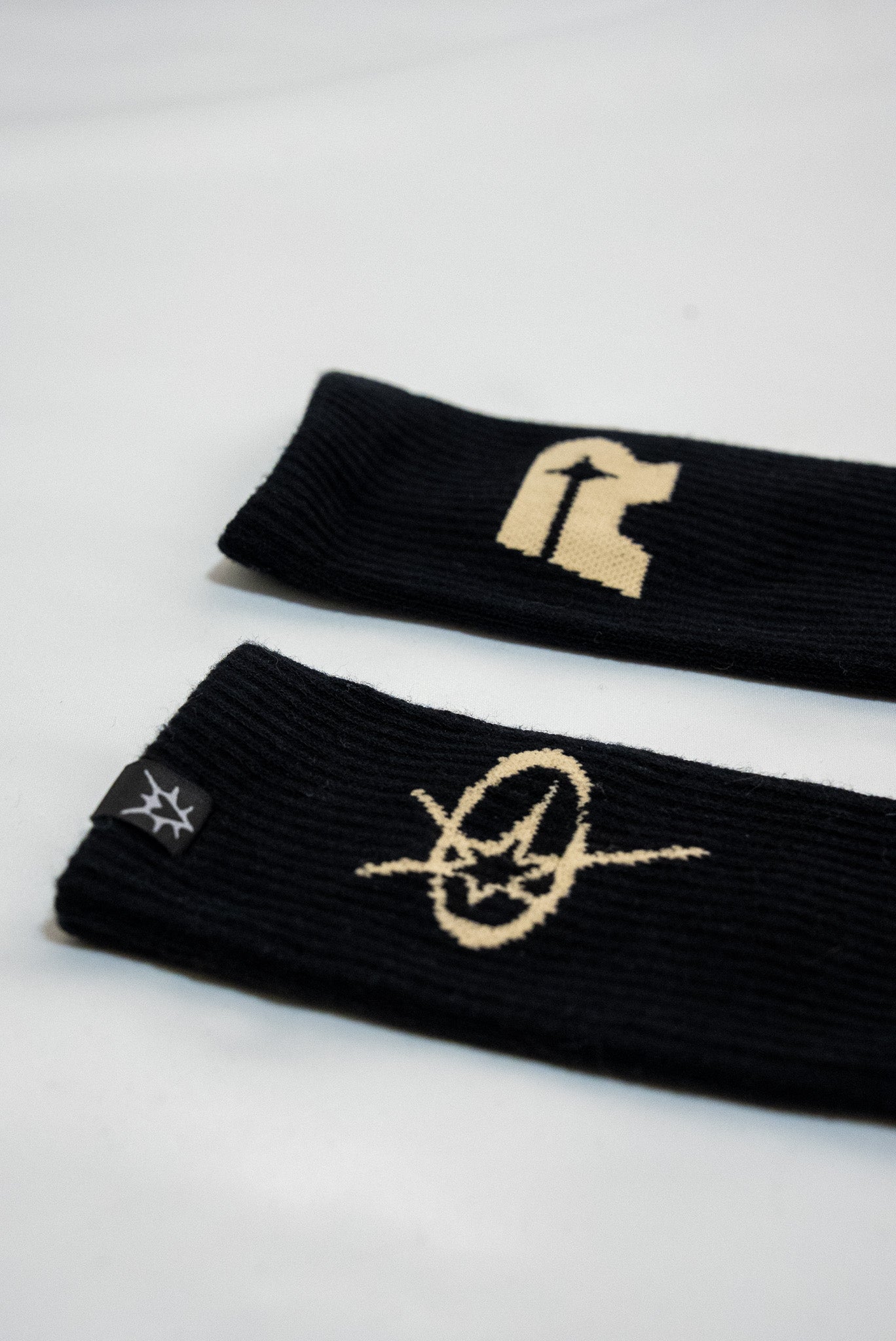 Two black socks with gold logos on a white background